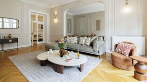 Ein geräumiges Wohnzimmer mit grauem Sofa, einem runden Couchtisch und einem Holznachttisch.
