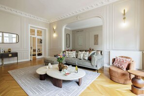 A spacious living room with a grey sofa, a round coffee table, and a wooden side table. - Prestige 280m² - Large Parisian apartment in the 16th arrondissement (Paris)