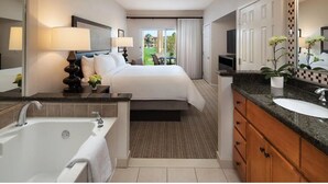 Habitación de hotel con una cama grande, un baño con bañera, lavabo y espejo.