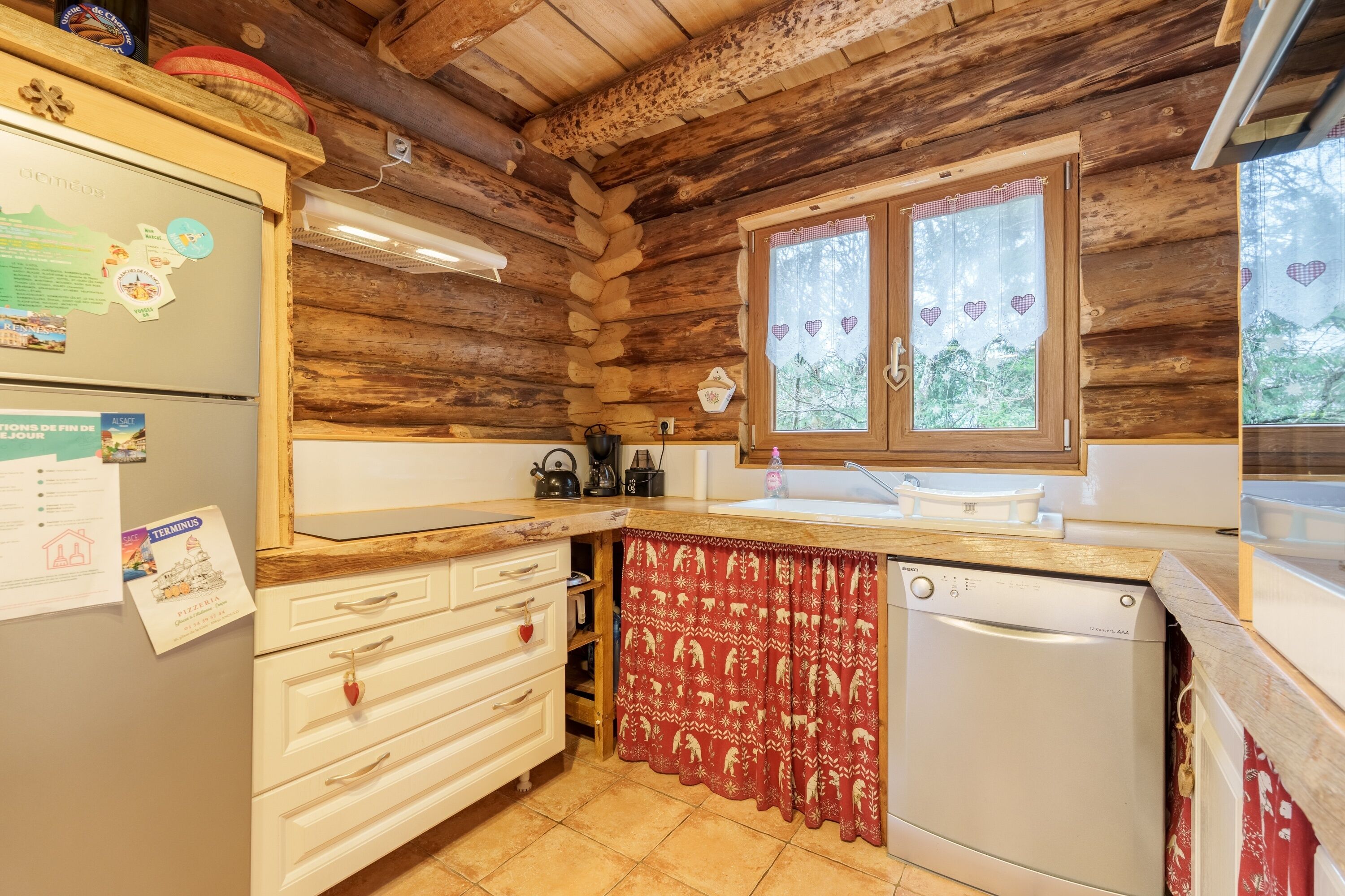 Une cuisine rustique avec des murs en bois, un réfrigérateur, un évier et un lave-vaisselle.