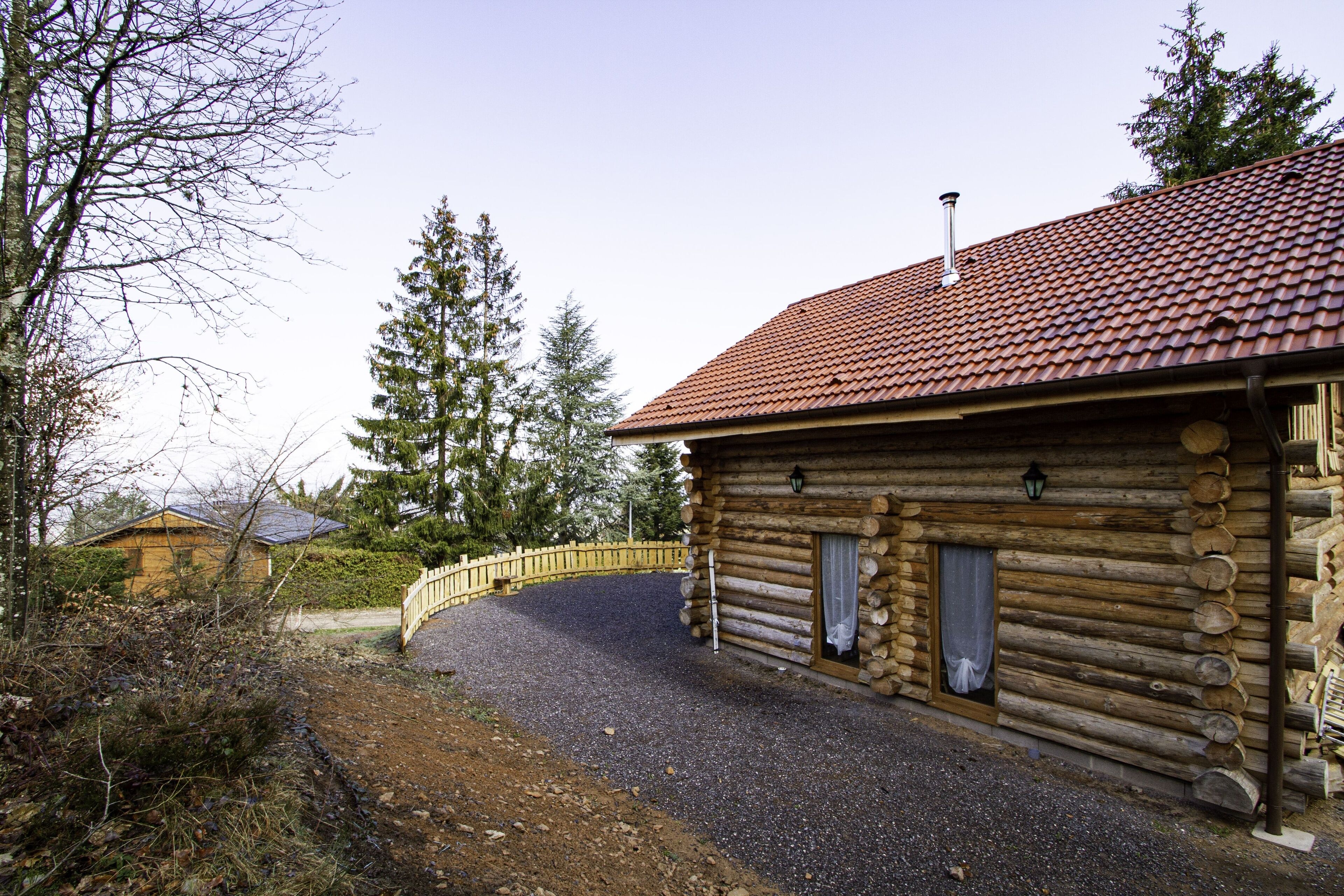 Eine Blockhütte mit einem Schotterweg und einem Holzzaun.