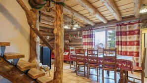 Interior rústico de madeira com escada, mesa de jantar e cadeiras.