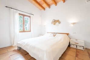 A bedroom with a bed, a nightstand, a window with curtains, and a wall-mounted light fixture. - Villa 'Finca El Colibri' with Mountain View, Wi-Fi and Air Conditioning (Manacor)
