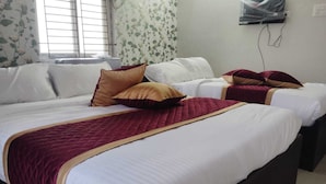 A hotel room with two beds, each with white linens and a red quilted bedspread.