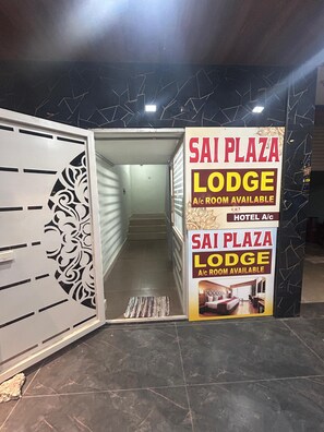 Entrada de un hotel con un cartel anunciando habitaciones con aire acondicionado en Sai Plaza Lodge.