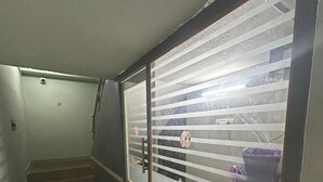 A narrow hallway with a metal railing and a glass door with horizontal blinds.