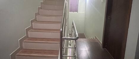 A staircase with a metal handrail, wooden steps, and a door labeled "STAFF" on the right.