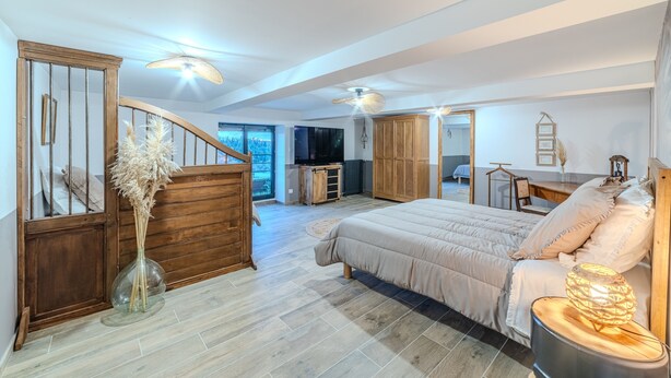 A spacious bedroom with a large bed, wooden wardrobe, and a view of the outdoors.