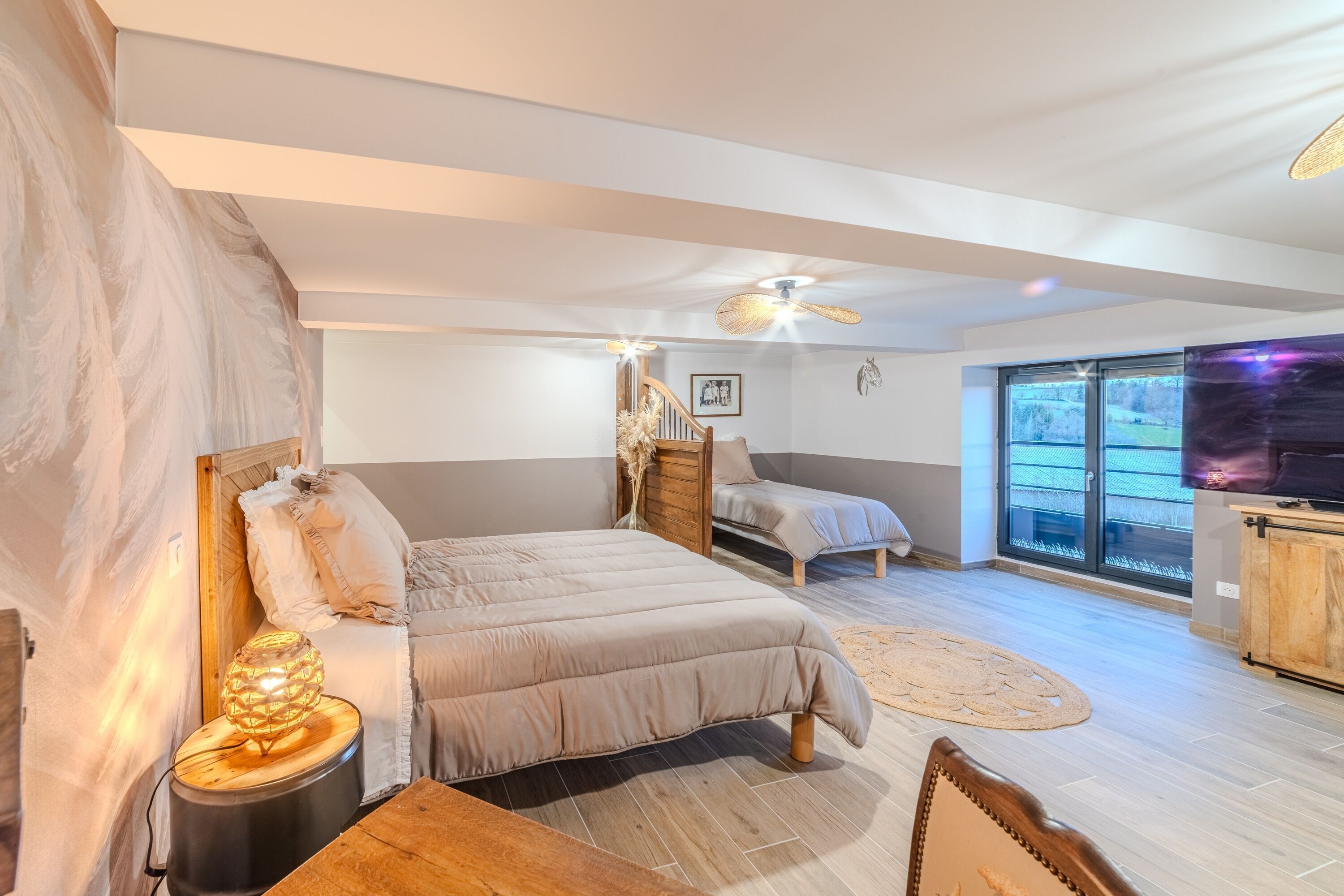 A bedroom with a bed, a desk, a chair, a TV, and a window.