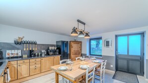 A modern kitchen with wooden cabinets, a central island, and a dining area set for six.