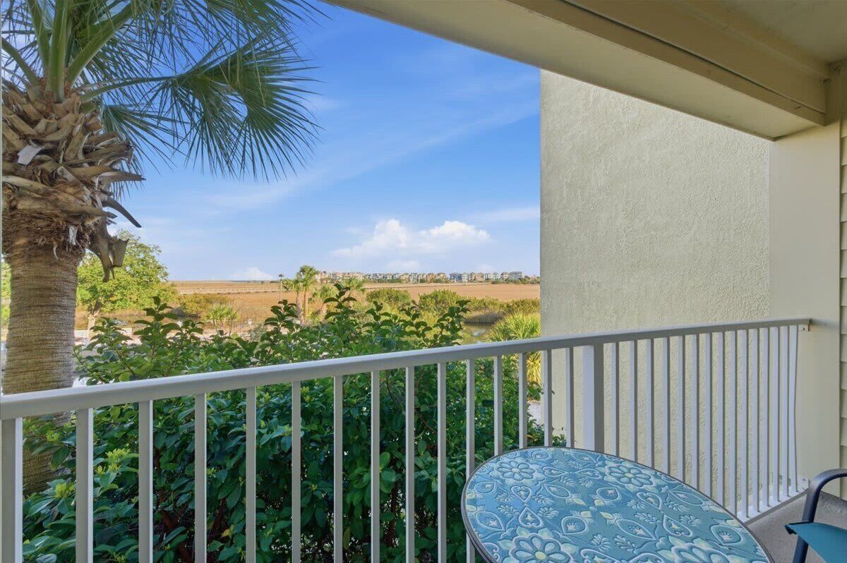 Un balcone con una palma, un tavolo e vista su un paesaggio lontano.
