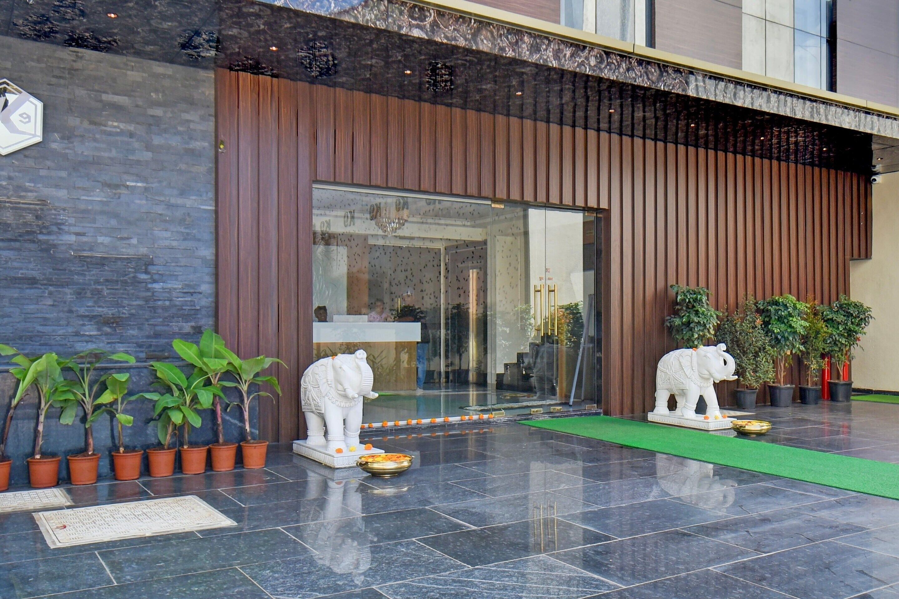 A modern building entrance with a reception desk, potted plants, and two elephant statues.