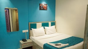 A hotel room with a bed, a nightstand, a telephone, and a wall-mounted mirror. - Hotel New 7AM  (Mumbai)