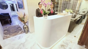 A reception desk with two staff members, a vase with dried plants, and a modern interior design. - Hotel New 7AM  (Mumbai)