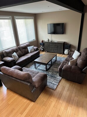 Ein modernes Wohnzimmer mit einer Eckcouch, einem Couchtisch und einem an der Wand montierten Fernseher.