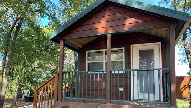 Een houten chalet met een veranda, een overdekt terras en een kleine tuin.