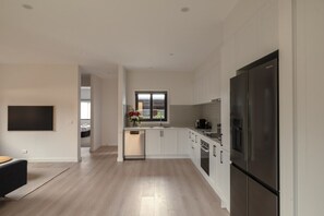 Una cocina moderna con armarios blancos, un refrigerador de acero inoxidable y una ventana con vistas al exterior.