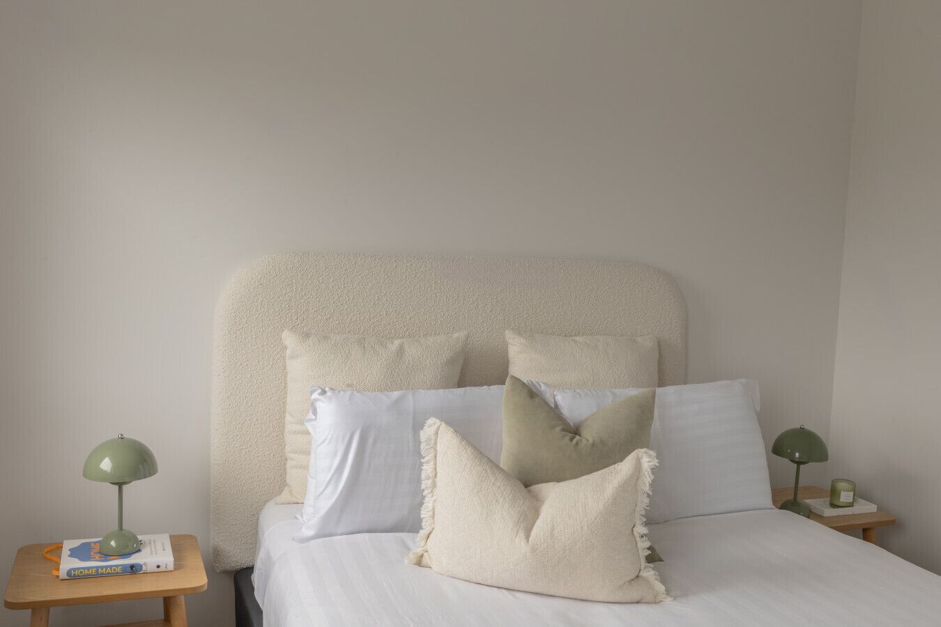 A bed with a fluffy headboard, multiple pillows, and two bedside tables with lamps.