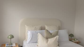 A bed with a fluffy headboard, multiple pillows, and two bedside tables with lamps.