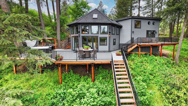 A two-story house with a deck, surrounded by trees. - Adullam Nature Escape - 10 acres in Colbert WA (Colbert)