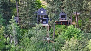 A cabin surrounded by dense forest, with a deck and a small outdoor seating area. - Adullam Nature Escape - 10 acres in Colbert WA (Colbert)