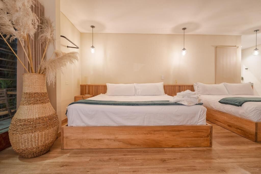 Un dormitorio con una cama de madera, ropa de cama blanca, una cesta tejida y una lámpara colgante.