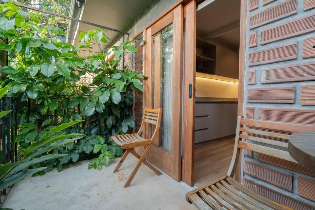 Puerta corredera de madera que da a una cocina con pared de ladrillo y un banco de madera en el exterior.