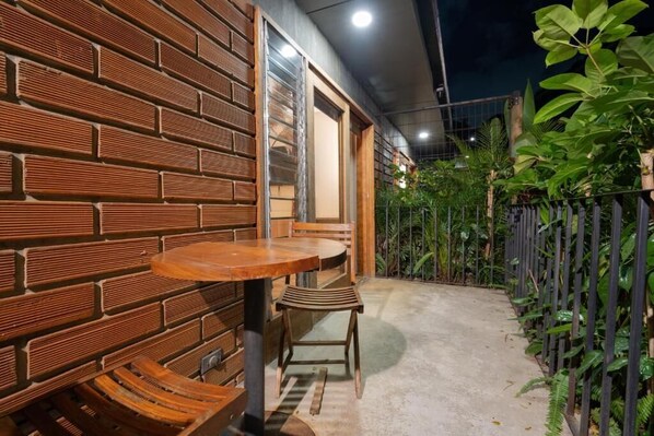 Un muro in mattoni con una panchina di legno e un tavolo, una porta e un giardino con piante.