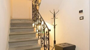 Eine Treppe mit Metallgeländer, einem Kleiderständer und einem Lautsprecher auf der Zwischenebene.