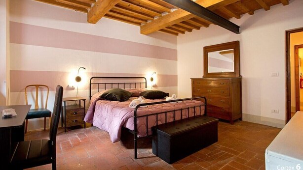 Ein Schlafzimmer mit einem Bett, Nachttischen, einem Sessel, einer Kommode und einem Spiegel.