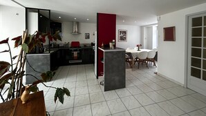 A modern kitchen with a central island, a dining area with a red accent wall, and a large window providing natural light. - Charming 6-person home with garden and jacuzzi in La Roche-Posay (La Roche-Posay)