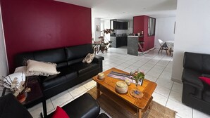 A modern living room with a black sofa, a wooden coffee table, and a red accent wall. - Charming 6-person home with garden and jacuzzi in La Roche-Posay (La Roche-Posay)