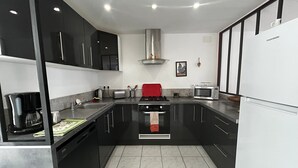A modern kitchen with black cabinets, a stainless steel range hood, a microwave, and a red towel on the stove. - Charming 6-person home with garden and jacuzzi in La Roche-Posay (La Roche-Posay)