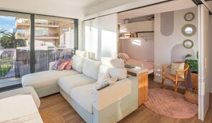 A modern living room with a large sectional sofa, a small desk, and a chair. There is a balcony with a view of the city. - Modern seaside apartment with view in Palamós (Palamós)