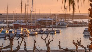 A marina with multiple boats docked, surrounded by a waterfront with bare trees in the foreground. - Modern seaside apartment with view in Palamós (Palamós)