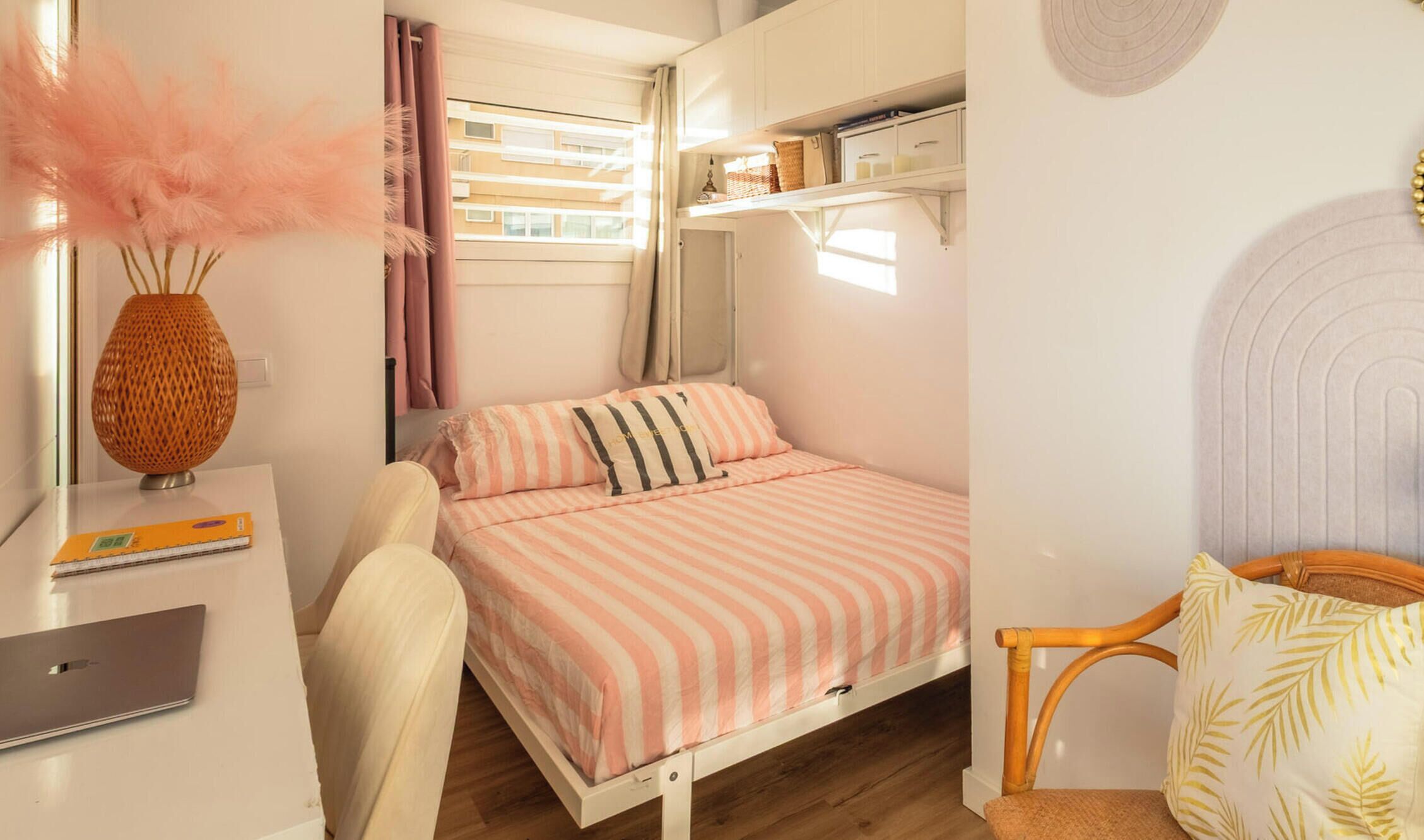 Ein gemütliches Schlafzimmer mit Bett, Schreibtisch, Stuhl, einer Bücherablage und einer dekorativen Vase.