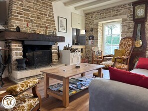 Una sala acogedora con chimenea de piedra, muebles de madera y un reloj en la pared.