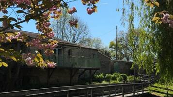 A stone building with a balcony, a bridge, and a weeping willow tree.
