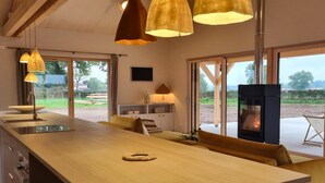 A modern kitchen with a large island, pendant lighting, and a fireplace. - Cozy Lodge in Vivans with Pool and Spa, Pets Allowed (Vivans)