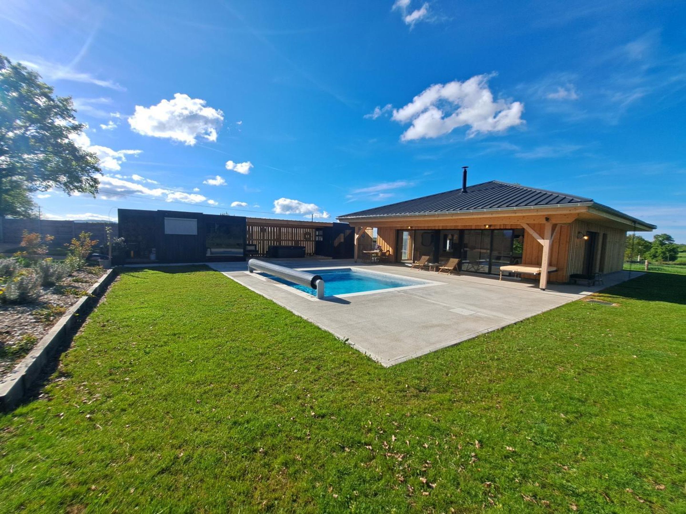 A modern house with a swimming pool, a covered patio, and a well-maintained lawn.