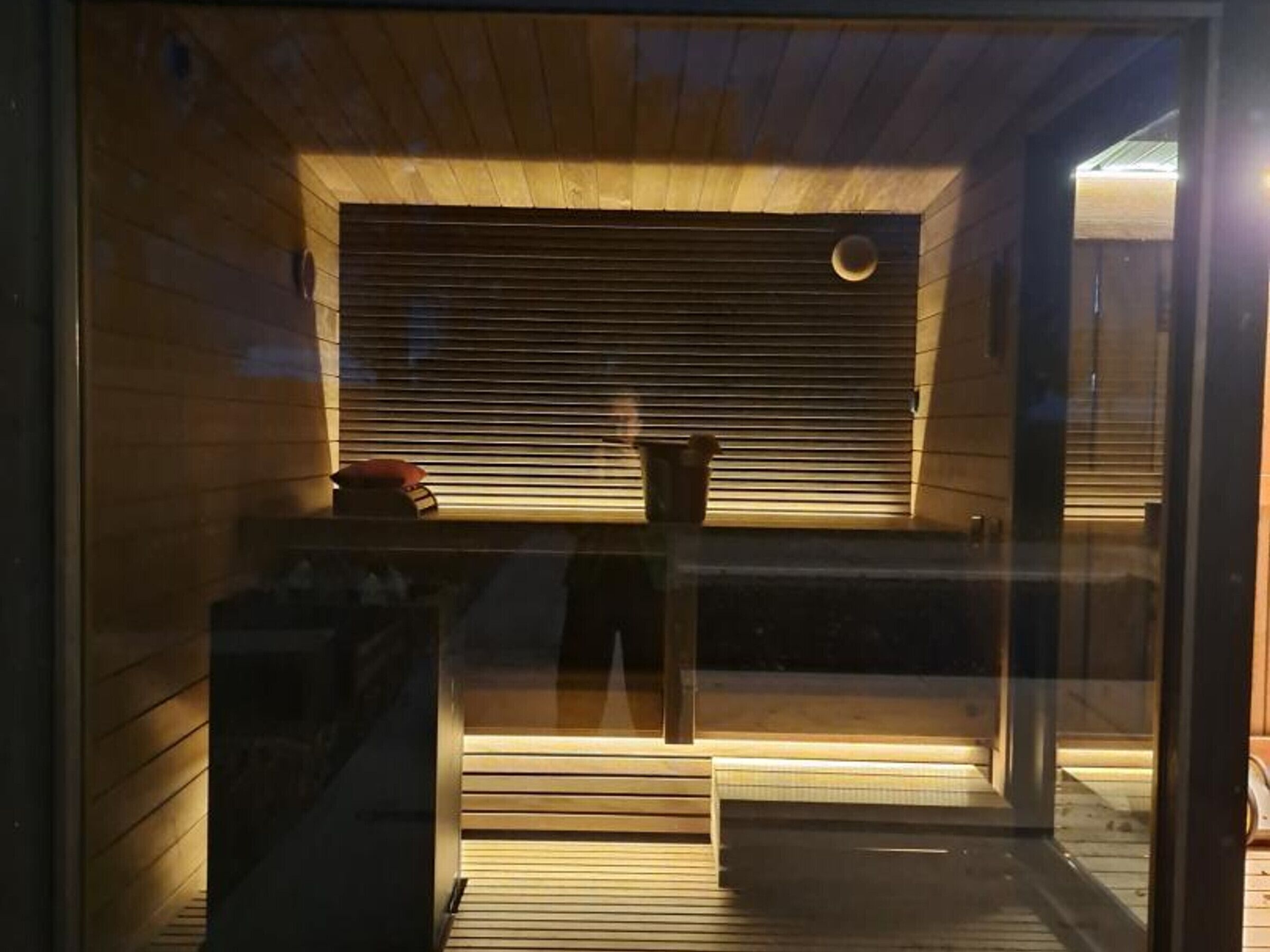 En sauna med træpaneler, bænk og et vindue med skodder.
