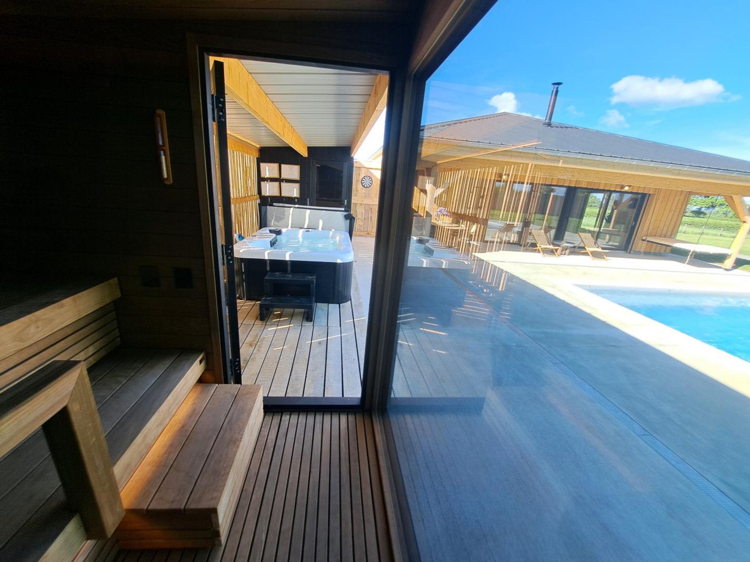 A wooden deck with a hot tub, a pool, and outdoor seating.