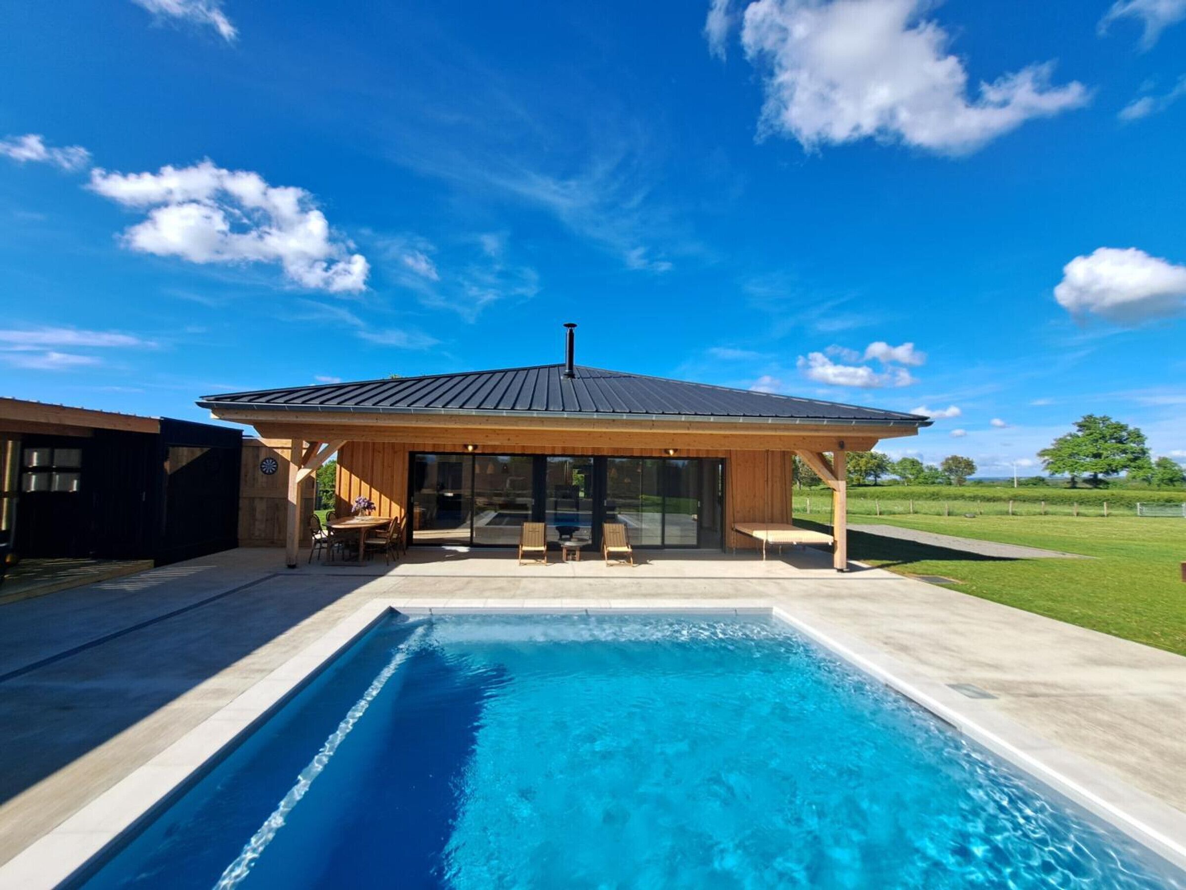 A modern house with a swimming pool, wooden deck, and a covered patio area.