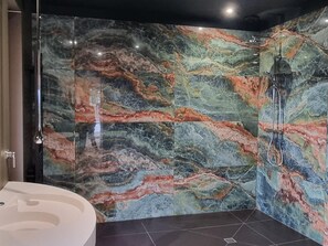 Ein Badezimmer mit Marmorwand, Dusche und Waschbecken.