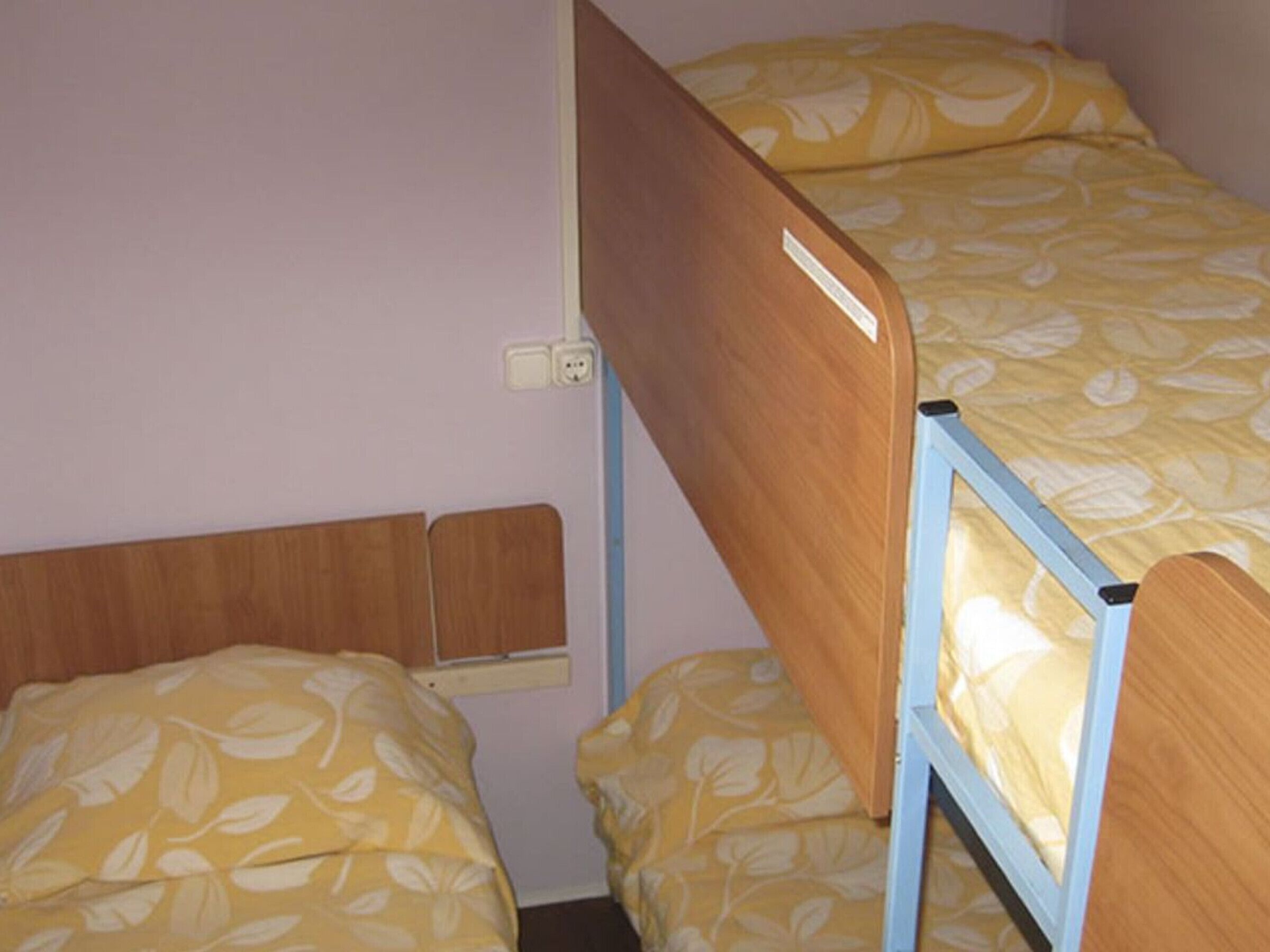 A bunk bed with a wooden frame and a mattress with a leaf pattern.