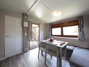 A compact room with a dining table, chairs, a sofa, a window with curtains, and a door. - Bungalow 5 People Zumaia with Terrace (Zumaya)