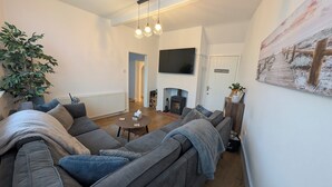 A modern living room with a sectional sofa, a fireplace, a television, and a large plant. - House in Martham (GREAT YARMOUTH)