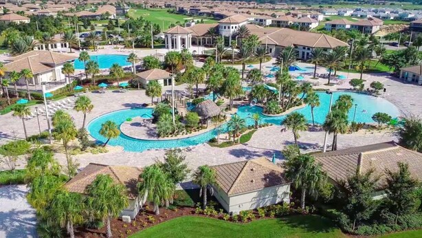 Um resort com várias piscinas, palmeiras e um campo de golfe ao fundo.