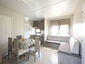 A compact living space with a dining area, kitchenette, and a seating area with a view. - Bungalow 2 Bedrooms 5 People - Terrace (Zumaya)