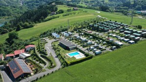 An aerial view of a campground with RVs, a swimming pool, and buildings with solar panels. - Bungalow For 4, Terrace - Zumaia, Spain (Zumaya)